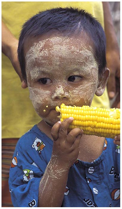 enfant eating corn in Myanmar, waiting for the boat
